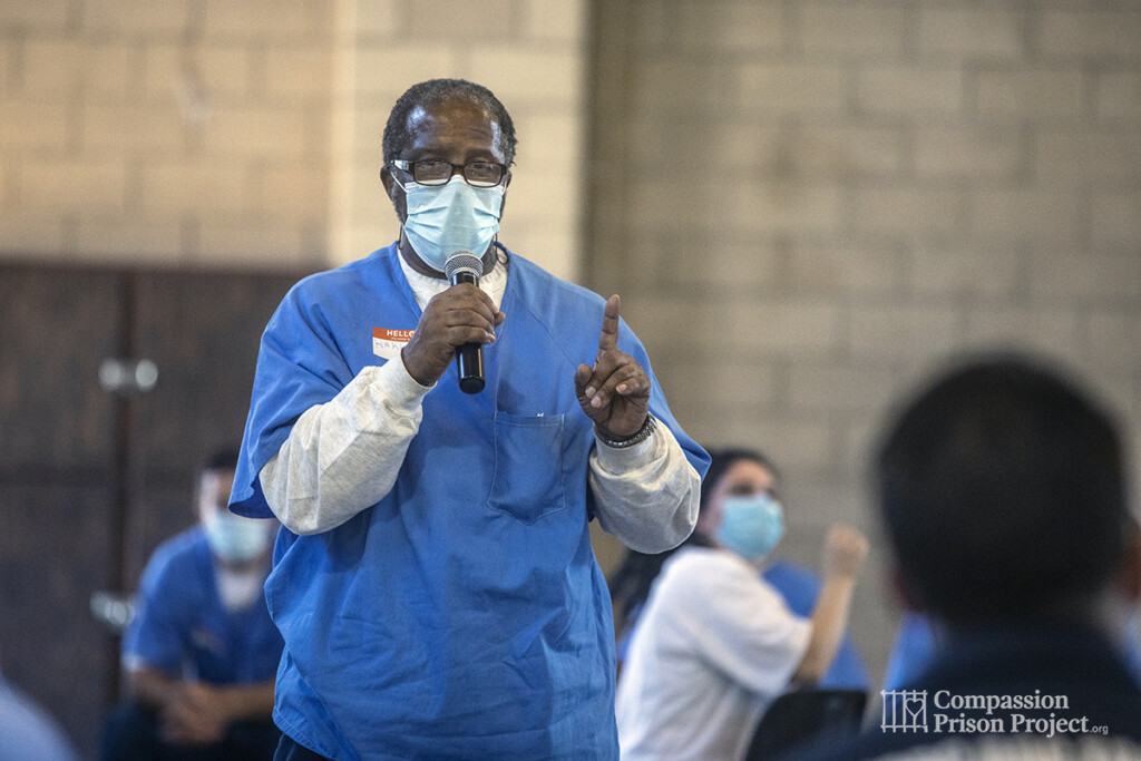 Man speaking into microphone wearing mask